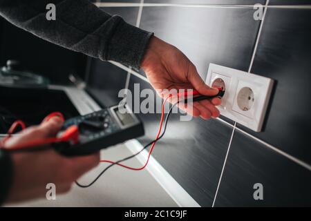 Electrician, Electrician installing new current socket with screwdriver. Installing electrical outlet or socket - closeup on electrician hands. Stock Photo