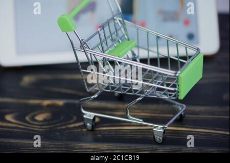 small shopping cart in front of a tablet as concept for online shopping Stock Photo