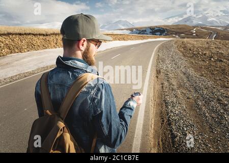 Hipster man using a compass on a snowy mountain Stock Photo