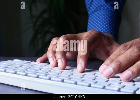 young man typing on keyboard at office desk Stock Photo