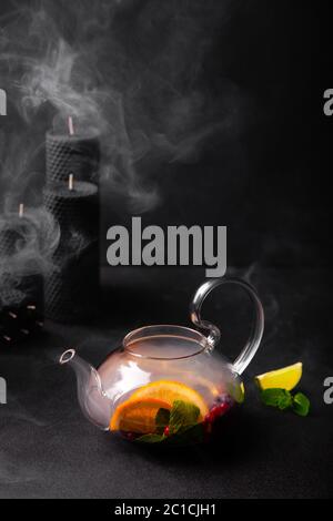 Pouring fruit tea in teapot with steam on black background Stock Photo