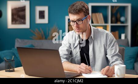 Man looking laptop making notes Stock Photo