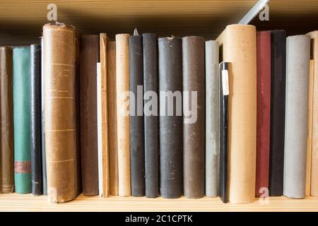 Many old dusty books in a library on a wooden shelve Stock Photo