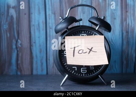 Tax Text on Adhesive Note on Alarm Clock. Stock Photo