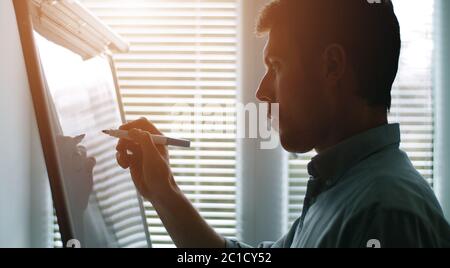 Businessman writing on whiteboard, side Stock Photo