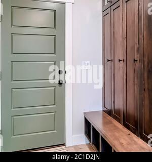 Square crop Panelled fire door with black knobs and lock adjacent to a tall vintage cabinet Stock Photo