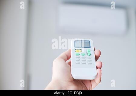 Air condition remote control. Hand with room conditioner remote control. Air temperature switch for cooling of space. Stock Photo