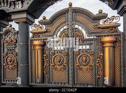 New forged metal massive gates with a wicket and two arches, golden gray, made in antiquity. Stock Photo