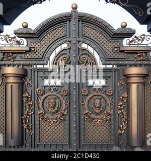 New forged metal massive gates with a wicket and two arches, golden gray, made in antiquity. Stock Photo