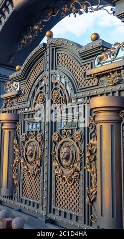 New forged metal massive gates with a wicket and two arches, golden gray, made in antiquity. Stock Photo