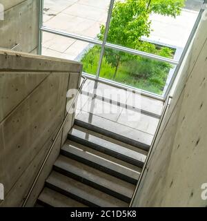 Square crop Commercial building interior with staircase and handrails between concrete walls Stock Photo