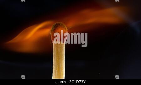 Burning wooden match with a red match head on a black background. Stock Photo