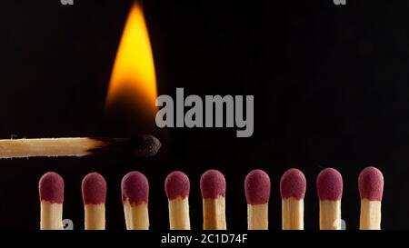 Burning wooden match with a red match head on a black background. Stock Photo