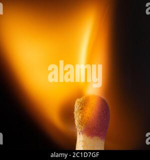 Burning wooden match with a red match head on a black background. Stock Photo