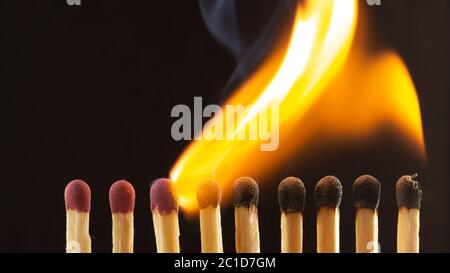 Burning wooden match with a red match head on a black background. Stock Photo