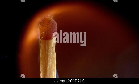 Burning wooden match with a red match head on a black background. Stock Photo