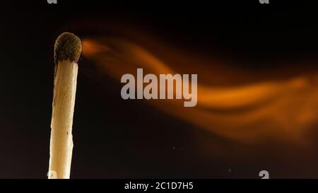 Burning wooden match with a red match head on a black background. Stock Photo