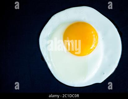 Fried egg isolated on rustic black background Stock Photo