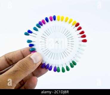 Person holding bunch of colorful brooches pin i his hand with his fingers Stock Photo