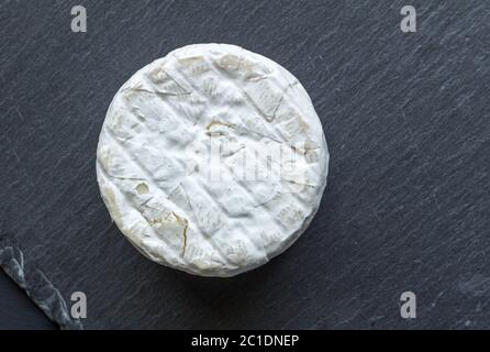 Whole round camembert cheese isolated on black slate board - top view Stock Photo