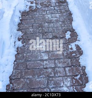 Square Close up of pathway paved with gray stone bricks amid deep layer of fresh snow Stock Photo