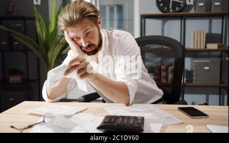 Puzzled businessman looking at bills Stock Photo