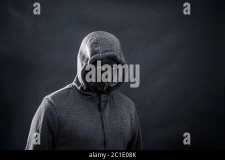 Hooded man with black mask in the dark Stock Photo