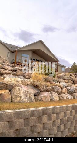 Vertical Dirt road along homes on a slope with huge rocks and concrete retaining wall Stock Photo