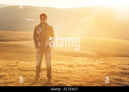 Fashion portrait of a bearded hipster young man wearing sunglasses, a backpack and hat on a background with copyspase in the mou Stock Photo