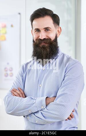 Portrait of a happy smiling bearded senior developer or manager in modern IT office. Stock Photo