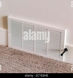Square Air conditioner white plastic grille cover against wall and carpet floor Stock Photo