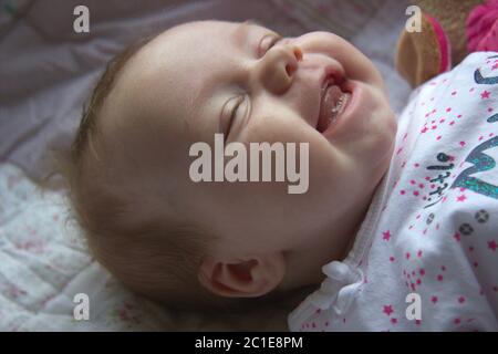 Beautiful expressive adorable happy cute laughing smiling newborn baby infant face showing tongue