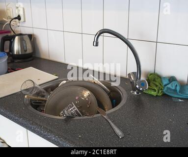 A lot of dirty dishes in the white sink in the kitchen Stock Photo