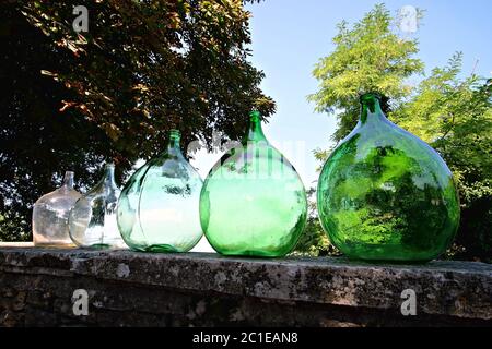 row of vintage glass carboys on a low wall Stock Photo
