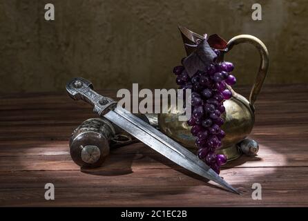 Beautiful example of caucasian dagger with silver powder flask and copper, jug on wood background. 19th century (Time of Russian-Caucasian wars (1816- Stock Photo