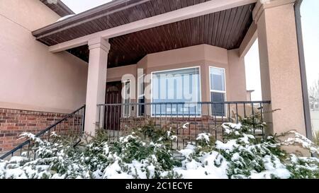 Panorama Snowy evergreens at the yard of brick home with bay window and front porch Stock Photo