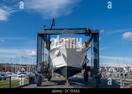 Large luxury motor yacht in a boat hoist, being lifted out of the water. Stock Photo