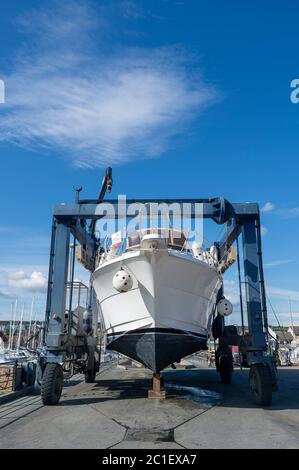 Large luxury motor yacht in a boat hoist, being lifted out of the water. Stock Photo