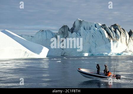 Fishing or cruising amongst the giant icebergs  calved from the glacier in the UBESCO World Heritage site at Ilulissat, Greenland. Stock Photo