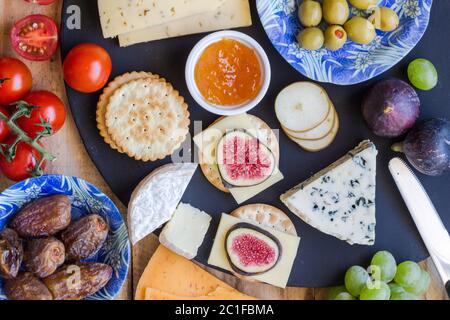 Cheese board close up with assortment of cheese, crackers, fruit and olives close up top view Stock Photo