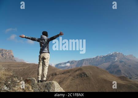 an applause of a young woman backpacker on top of a sprawling upward mountain peak. Freedom and victory against the background o Stock Photo
