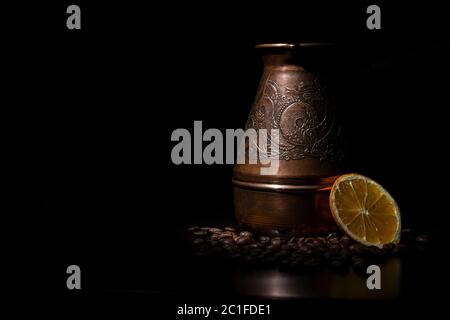 Coffee vessel with coffee beans and a lemon slice on a black background. Stock Photo