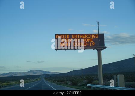 avoid gatherings stay at home beat COVID-19 highway sign near dusk Stock Photo