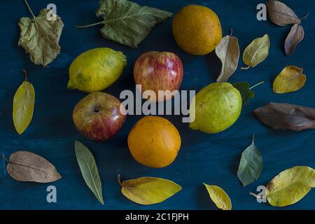 Some oranges, lemons, apples and leafs on a blue background Stock Photo