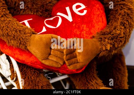 Two soft toy monkeys sit arm in arm in a small car, holding a fabric heart in their hands Stock Photo