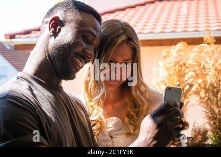 Young woman and man looking at phone together. Medium shot. Side view. Stock Photo