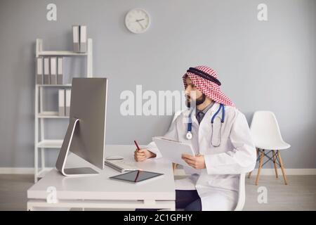 Young ethnic doctor working with computer in office Stock Photo
