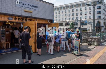 Tourists at the boat cruise ticket counter in Otaru Canal, Hokkaido, Japan Stock Photo