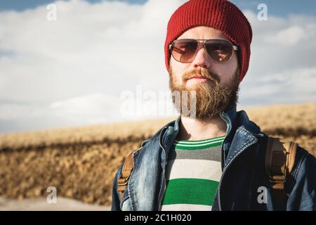 Portrait of a young hipster man wearing sunglasses and a hat. A smiling bearded man wearing sunglasses. Happy man with a beard Stock Photo