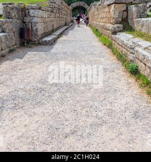 Olympia, Greece - September 7, 2014: Tourists entering crypt. Crypt is the vaulted tunnel leading into the ancient Olympia Stadium, Peloponnese, Greec Stock Photo